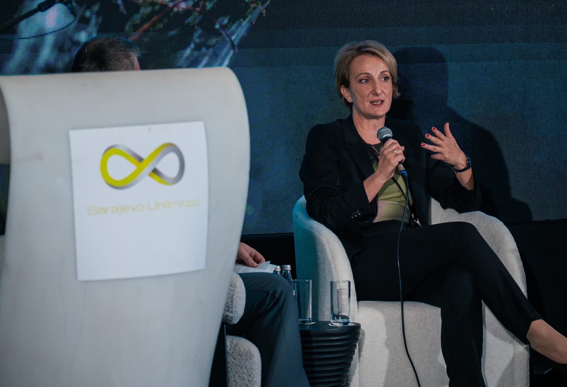Panelistkinja gestikulira dok govori, logo Sarajevo Unlimited na fotelji u prvom planu