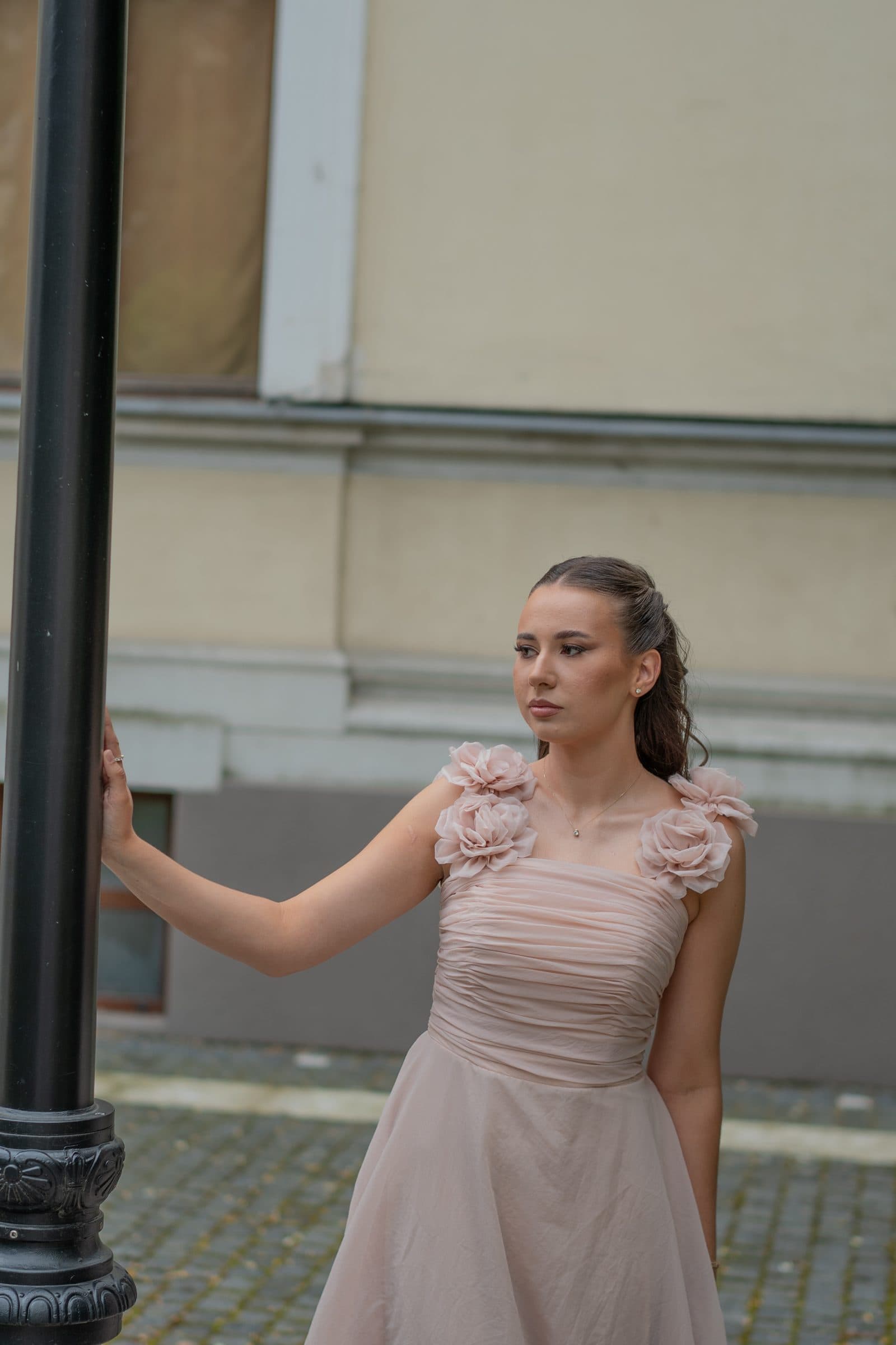 Sumeja holding a black street lamp, looking away