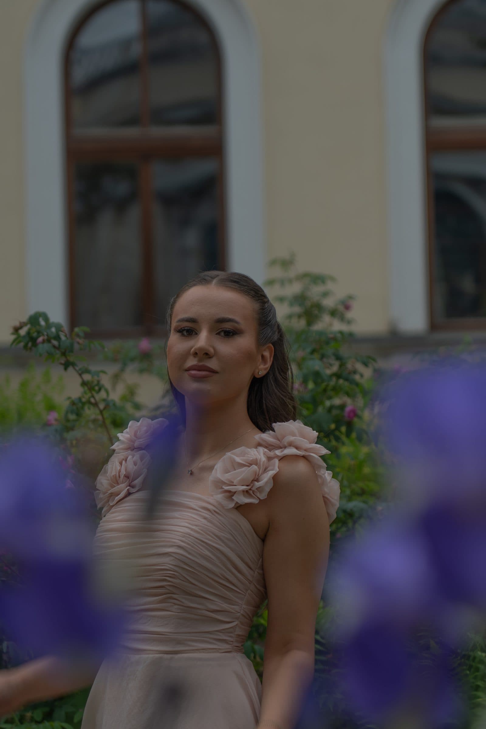 Sumeja framed by blurred purple irises, arched windows behind her