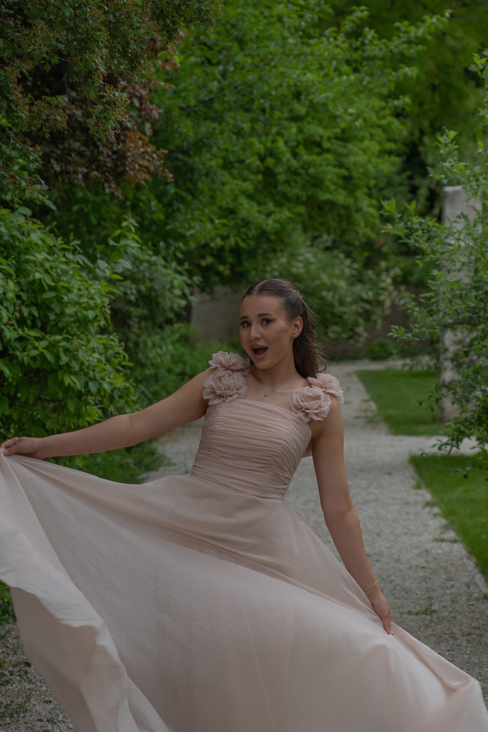 Sumeja playfully swirling her gown on a garden path
