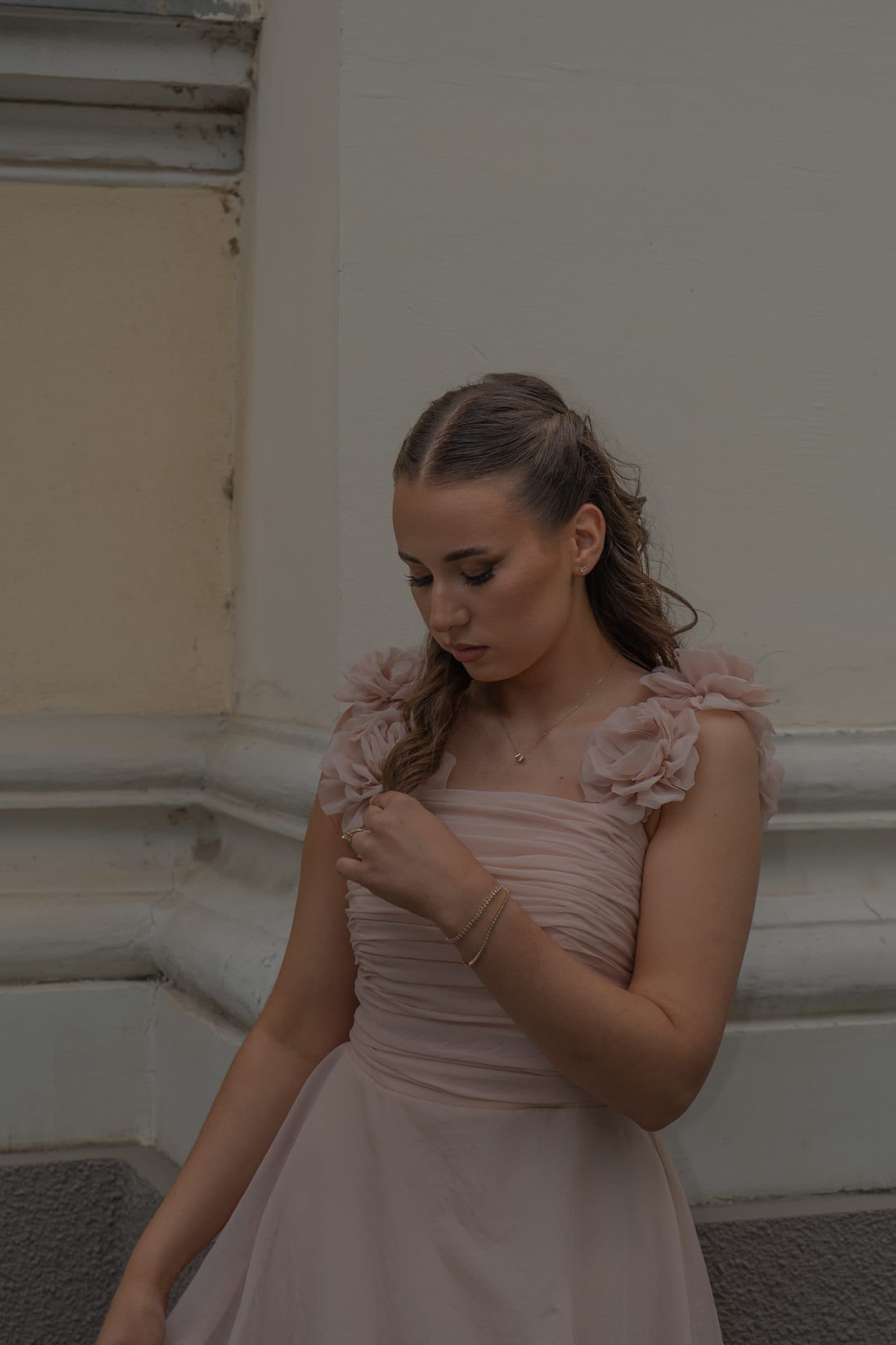 Sumeja looking down, holding the rose strap of her gown